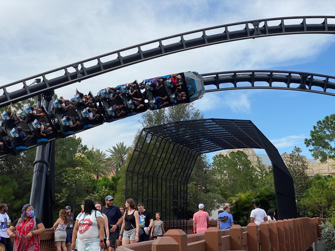 Picture of Velicoaster going sideways over guests walking on bridge at Islands of Adventure in Universal Orlando